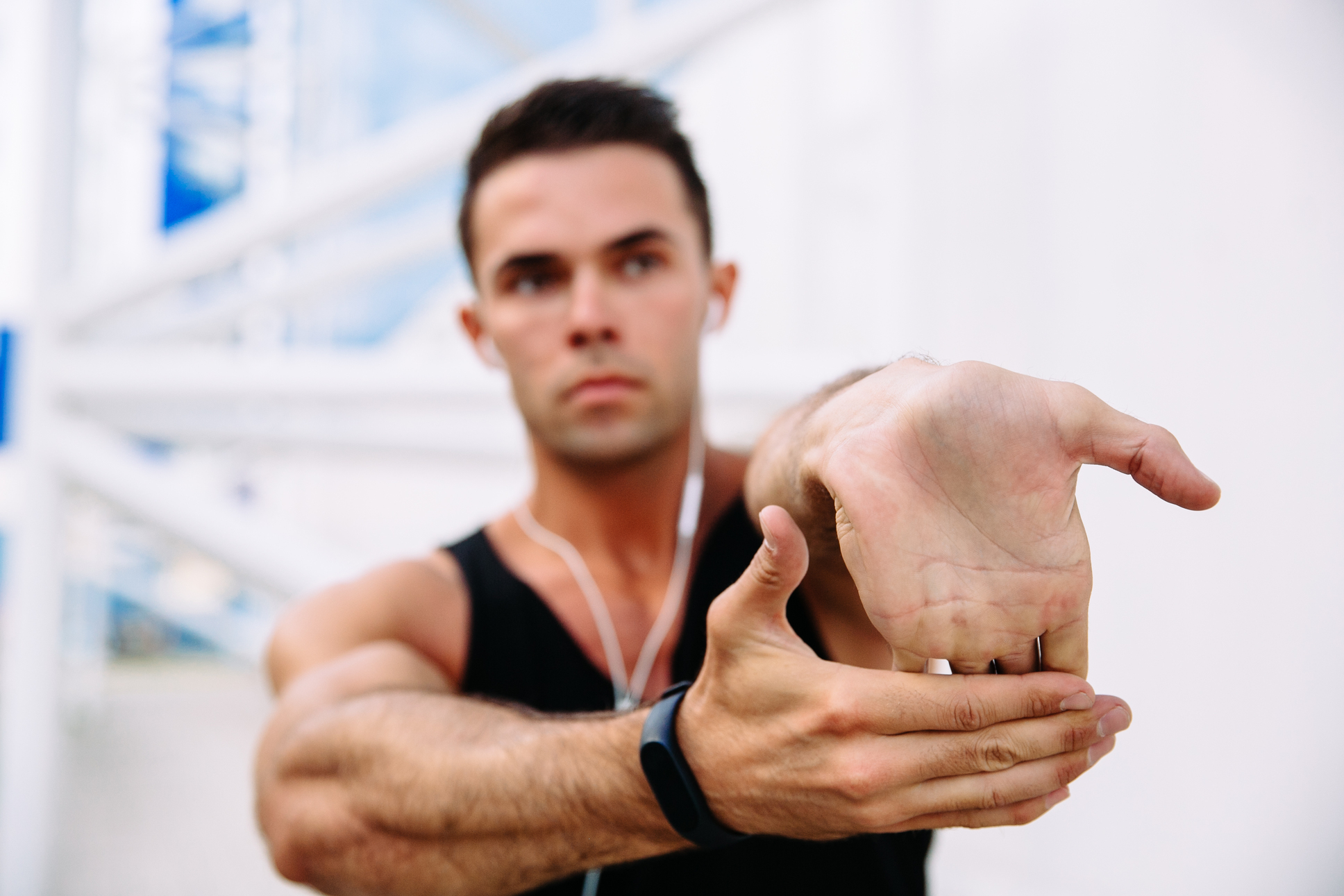 close-up of a man stretching his wrist with an extended arm, wearing a fitness band